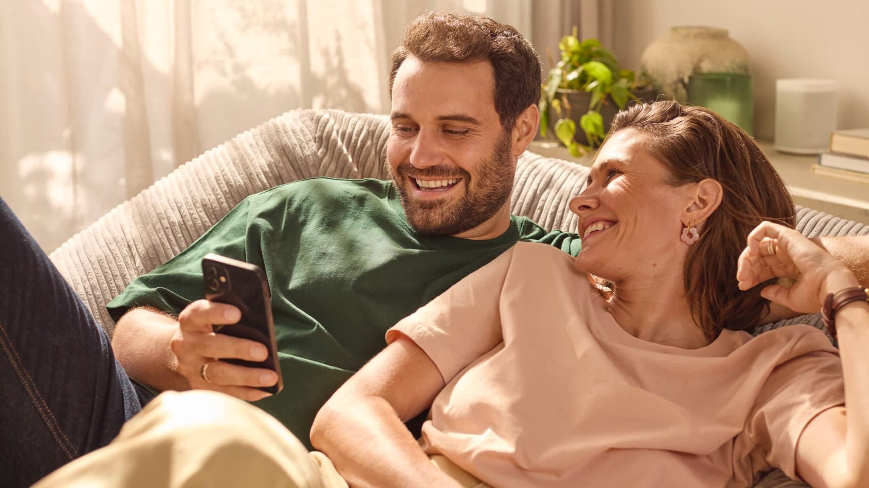 Par sjedi na kauču i gleda u telefon