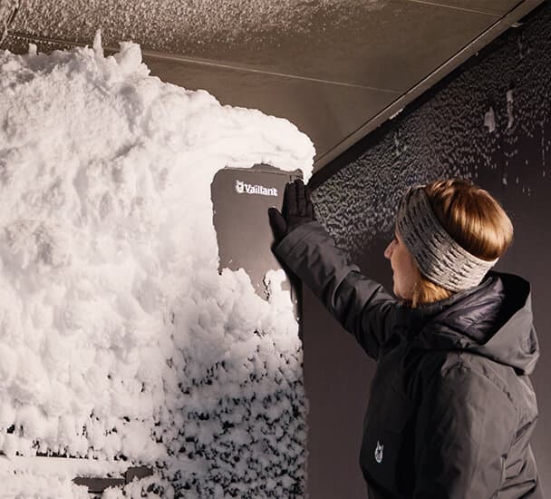 Žena ispred aroTHERM plus prekrivenog snijegom