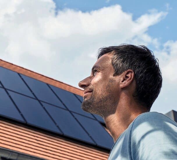Muškarac gleda prema krovu na kojem se nalaze solarni paneli