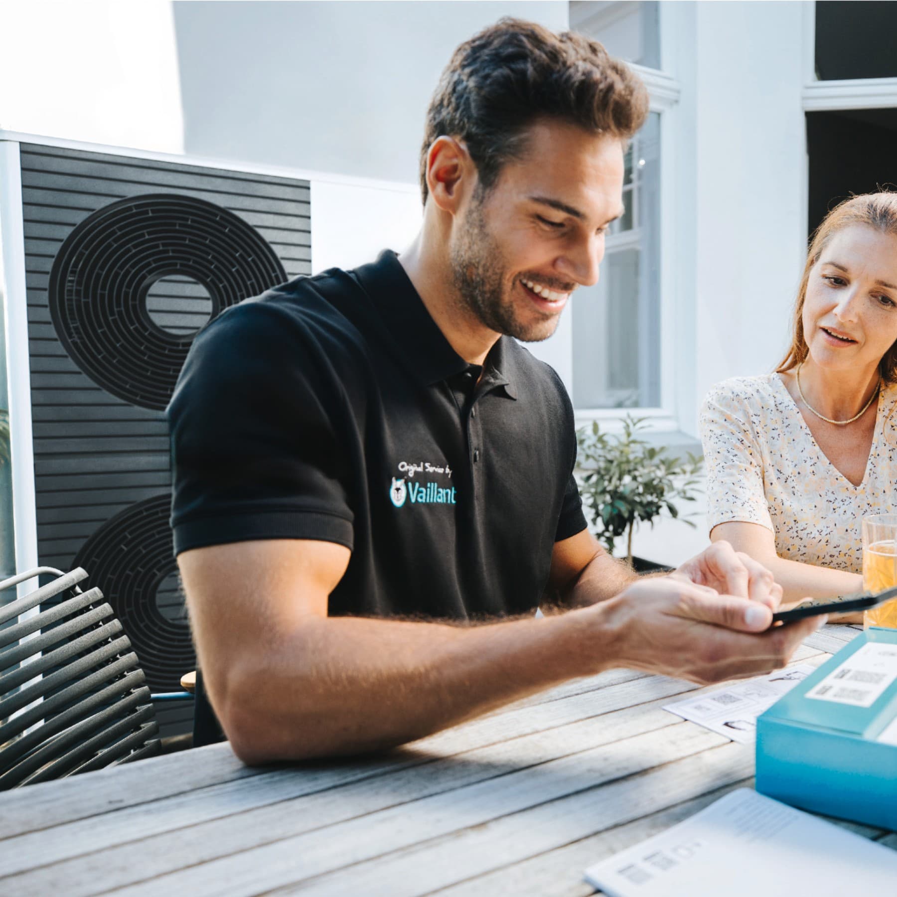 Vaillant instalater sa pametnim telefonom u ruci i kupac koji sjedi pored njega